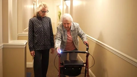 Closeup of senior elderly mother using a walker with mature daughter walking Stock Footage 253404650