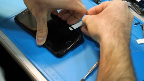 Closeup serviceman removes dust from under iphone film cover Stock Footage 104656342