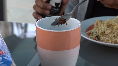 Closeup serving coffee beans from a package to a cup with water with a teaspoon Stockbeeldmateriaal 161938314