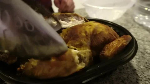 Closeup serving a grilled chicken in a black plastic container brought by Stockbeeldmateriaal 181899557