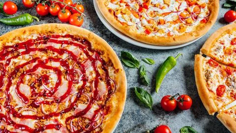 Closeup of a set of pizzas on a table with vegetables Stock Photos