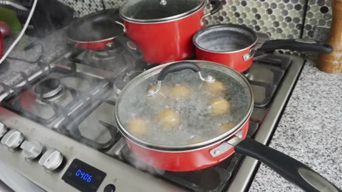Closeup of several eggs in a pot with boiling water in a kitchen and steaming in Vidéo 185330668