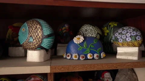 Closeup of several painted stones in the shape of fish and roses Vidéo 140390632