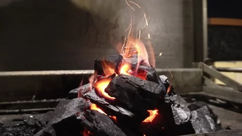 Closeup of several pieces of charcoal burning in fire flames and throwing ashes Video stock 193023650