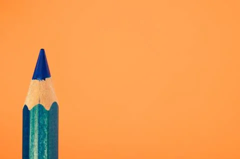 Closeup of a sharp blue pencil isolated on an orange background Stock Photos