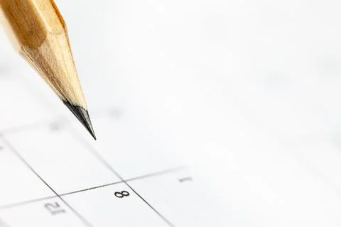 Closeup of sharp graphite pencil on white paper of calendar.  Concept of In.. Stock Photos