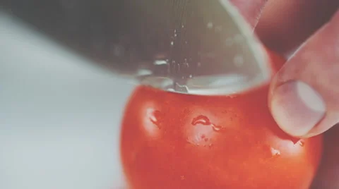 Closeup of sharp kitchen knife cutting slices of tomato. Macro Stock Footage 64235899