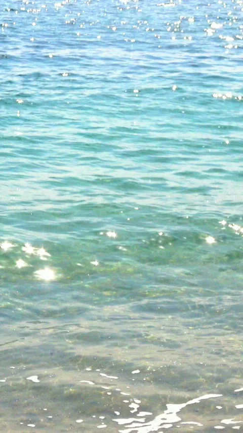 Closeup of the shimmering sea waves rushing toward shore on beach with sounds. Stock Footage 338367516