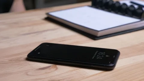 Closeup shoot of female hand taking a phone laying on the desk next to the Video stock 108740102