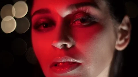 Closeup shoot of pretty female face with stunning makeup with red neon light and Video stock 106936253
