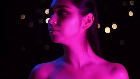 Closeup shoot of young stunning caucasian female with pink neon light and bokeh Video stock 106928915