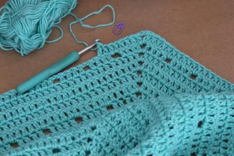 Closeup shot of a blue string in a crochet pattern and tools Stock Photos