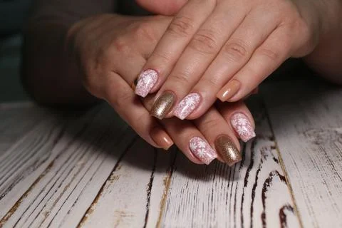 Closeup shot of brown manicure with patterns of female's nails on a wooden backg Stock Photos