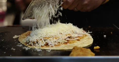 Closeup shot of a chef grating cheese while making Veg Frankie Wrap Roll Stock Footage 169833179