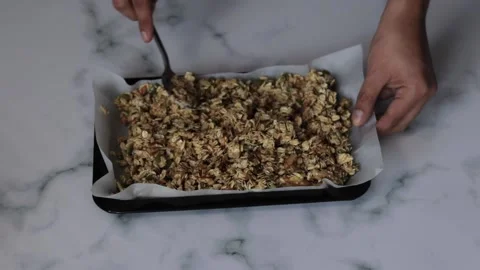 A closeup shot of a chef spreading an oat mixture onto a baking sheet granola Stock Footage 139260083