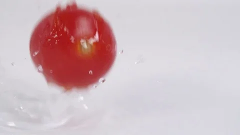 Closeup shot of cherry tomato falling into white dish for food preparation Video stock 72512496