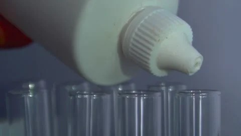 Closeup shot of dropping liquid/Orange liquid into test tube. Stock Footage 323780571