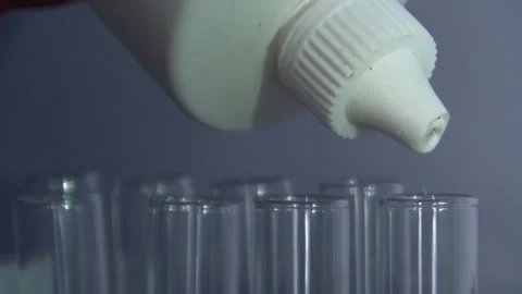 Closeup shot of dropping liquid/Orange liquid into test tube. Stock Footage 323781692