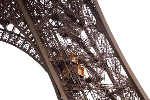 Closeup shot of the Eiffel Tower with an elevator behind iron bars on a cloudy d 스톡 사진