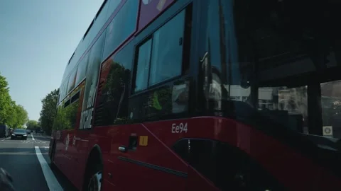 Closeup shot of a famous double decker red bus passing on streets of London, UK Stock Footage 314776203
