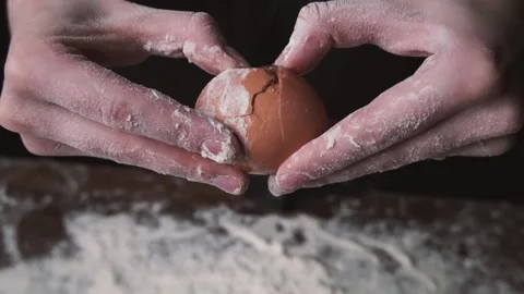 Closeup shot of female chef cracking egg in flour. Slow motion of falling eggs Stock-Footage 131237876