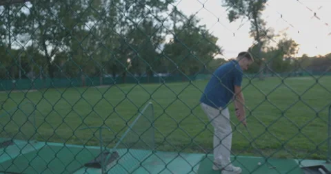 Closeup shot of a golf player through a metallic net at Adi Ciganlija, purple sk Stock Footage 221348516
