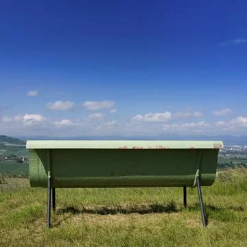 Closeup shot of a green rusty bench on a cloudy sky background Stock Photos