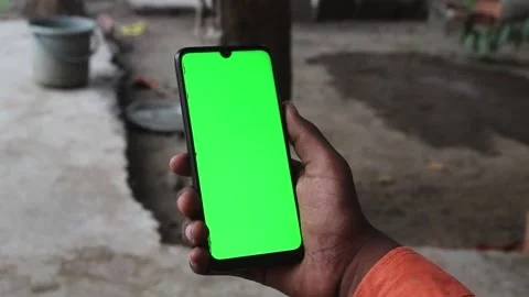 Closeup shot of hand holding mobile with green screen in a rural setting Stock Footage 139970606