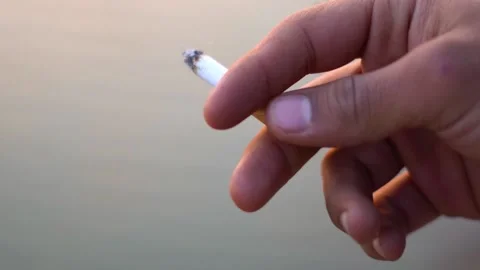 cigarette in hand pic indian Closeup shot of hand of an Indian man holding burning cigarette