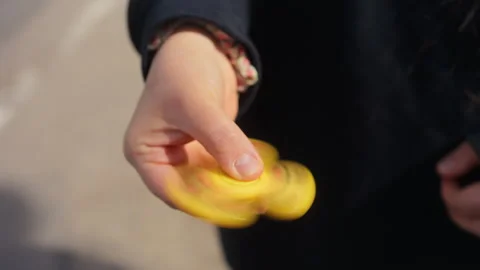 A CloseUp Shot of a Hand Skillfully Spinning a Colorful Fidget Spinner on the Stock Footage 308334910