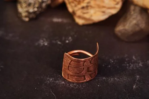 A closeup shot of handmade curved rectangular lava shape copper ring on black Stock Photos