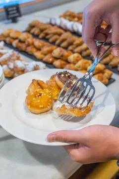 Closeup shot of human hand picking assorted pastry at buffet Stock Photos