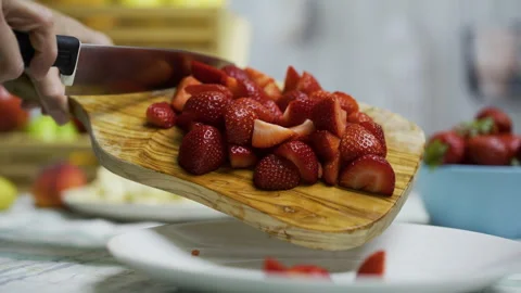 Closeup shot of knife being used to move sliced strawberries onto plate Stock Footage 341184555