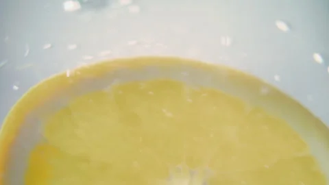Closeup shot of lemon slice falling in water and making bubbles Stock Footage 276758048
