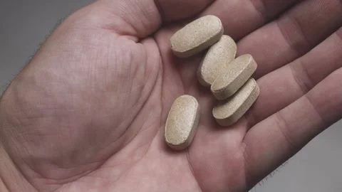 Closeup shot of light colored pills and tablets in open hand Stock Footage 342240029