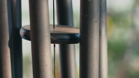 Closeup shot of the light wind moving a black wind chimes hanging outdoors in Vidéo 254471835