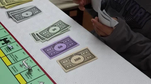 Closeup shot of a little boy counting paper notes for a game of Monopoly Видео 271048899
