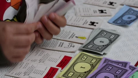 Closeup shot of a little boy counting paper notes for a game of Monopoly Stock Footage 271048927