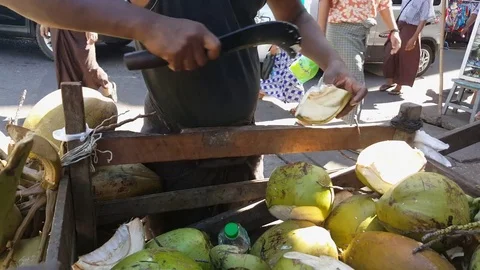 Closeup shot of man cuts coconut, coconut cart, pedestrians, cars, clothes Vídeos de archivo 77817063