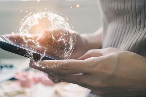 Closeup shot of a man using a phone with a 3D rendering of a globe coming out of 写真素材