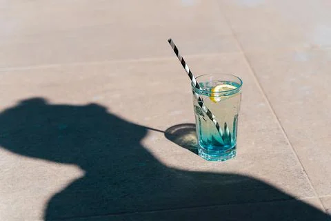 Closeup shot of man's shadow drinking sparkling mint lemonade tropical cocktail Stock Photos