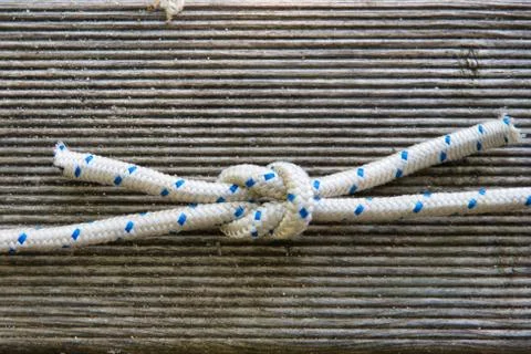Closeup shot of Nautik cross knot made of white shoelaces with blue dots Stock Photos