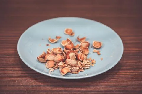 Closeup shot of nutshells in a blue plate on a wooden surface Stock Photos