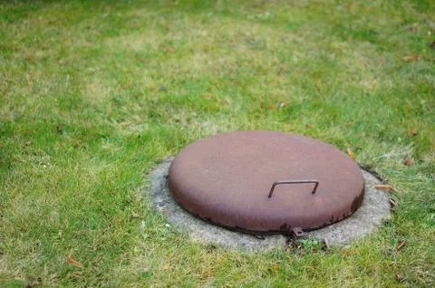 Closeup shot of an old closed hatch in a grass field Stock Photos