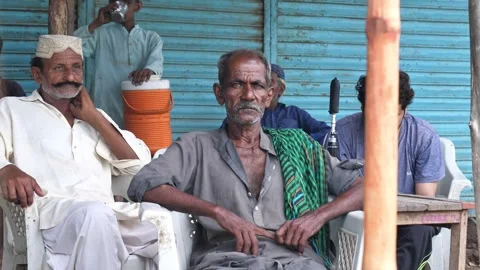Closeup shot of an old Pakistani man sitting on chair with his friends during Stock Footage 313986828