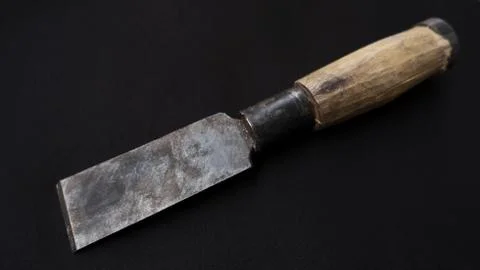A closeup shot of an old rusty chisel with wooden handle isolated on a black  Photos