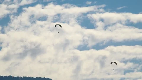 Closeup shot of parachutes in front of clouds and mountains.  Video stock 187398433