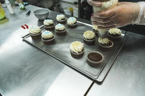 Closeup shot of person adding vanilla buttercream frosting with pastry bag onto Stock Photos