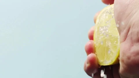 Closeup shot of person's hands squeezing lemon juice. Human squeezes half of Stock-Footage 336588545