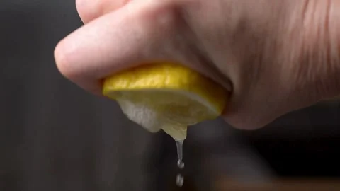 Closeup shot of person's hands squeezing lemon juice. Human squeezes half of Stock-Footage 336588593